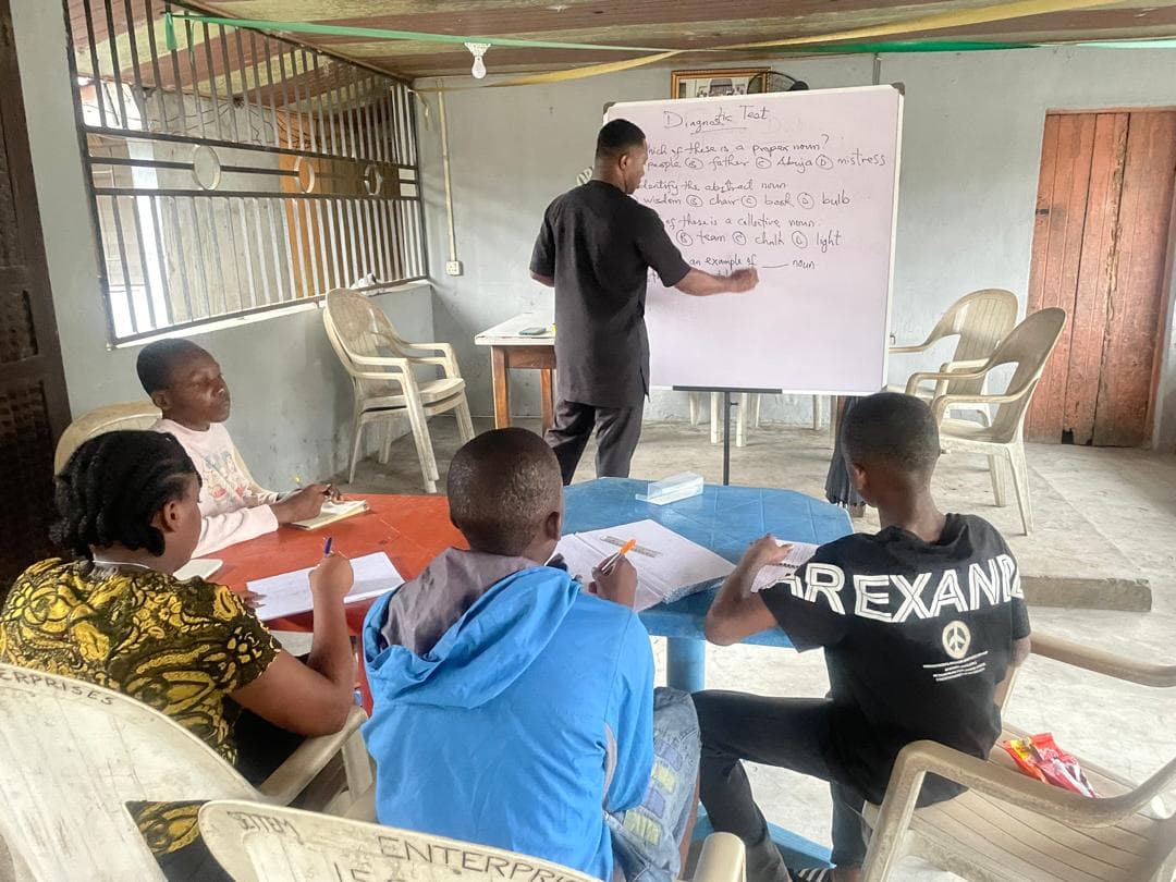 A facilitator leads a leadership session at a whiteboard with students seated around tables.
